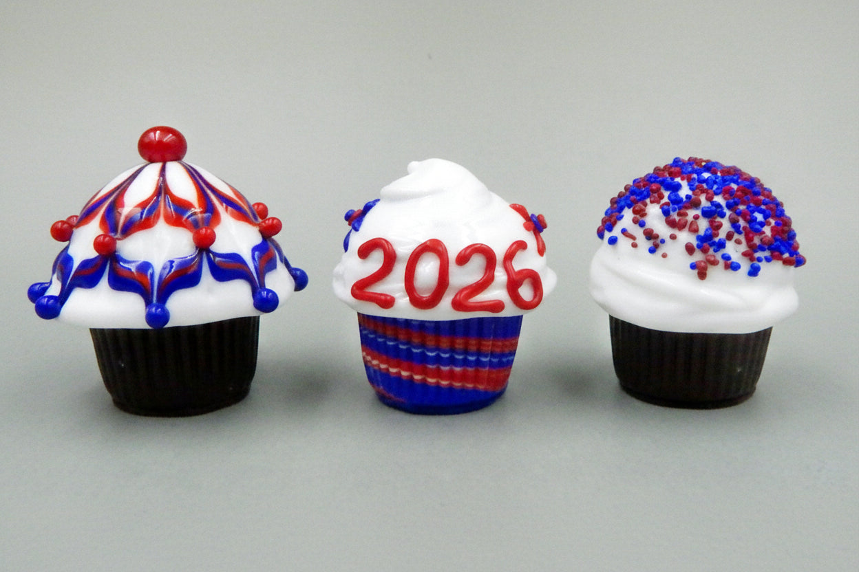 Three decorative cupcakes with red, white, and blue icing on a gray background